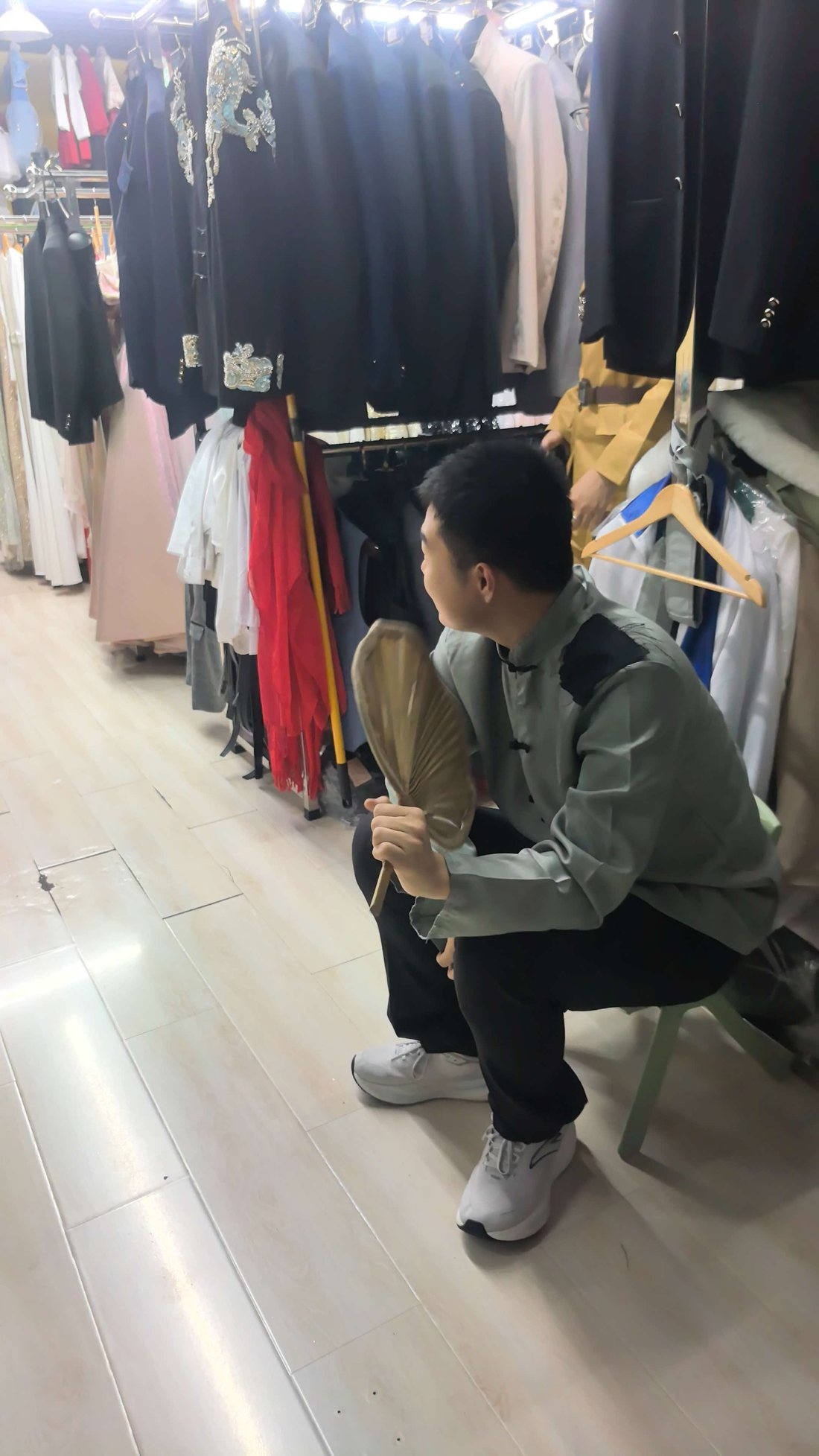 服装店里蹲坐小凳手持蒲扇的人